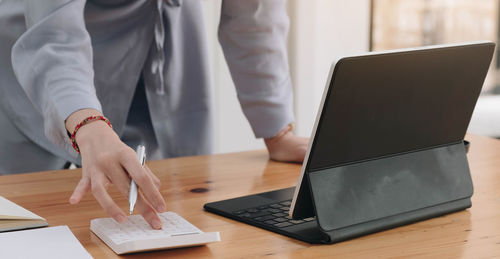 Midsection of woman using laptop on table