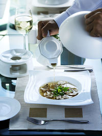 Cropped hand pouring soup in bowl on table