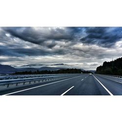 Road passing through landscape against cloudy sky