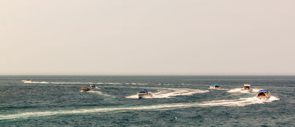 People in boats on sea against sky