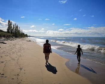 Rear view of women on beach against sky