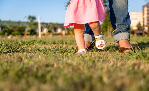 Low section of mother with cute daughter on field