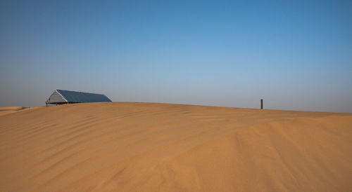 Sand dunes in desert against clear blue sky