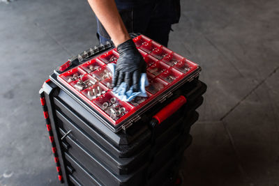 Unrecognizable male mechanic spraying tool box with detergent during work in professional garage