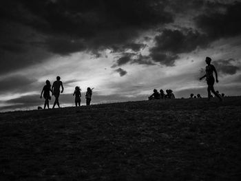 People on field against cloudy sky