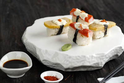 Tamago sushi and crabstick roll on wooden table