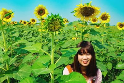 Portrait of smiling young woman against sunflower plants