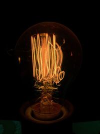 Close-up of illuminated light bulb against black background