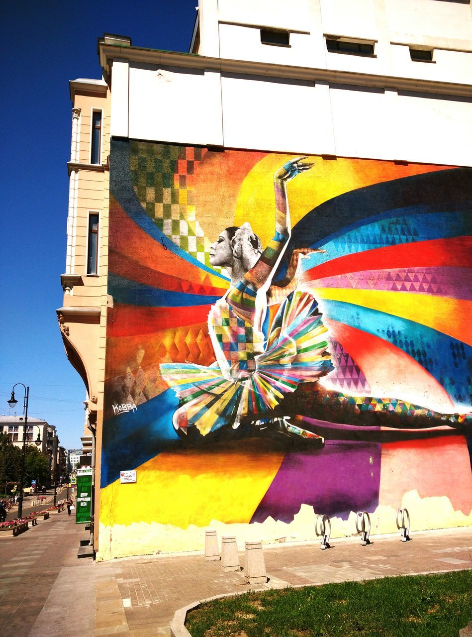 building exterior, built structure, architecture, low angle view, art and craft, sky, graffiti, clear sky, art, creativity, outdoors, day, sunlight, blue, multi colored, no people, house, wall - building feature, building, city