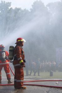 Rear view of fire woman standing by waterfall