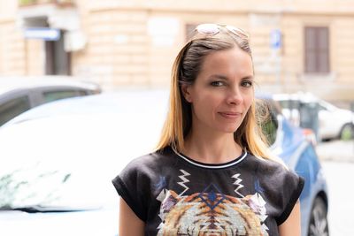 Portrait of smiling young woman against car