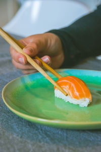 Cropped hand of person holding sushi in plate