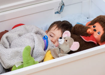 Cute baby is sleeping in a box with his toys