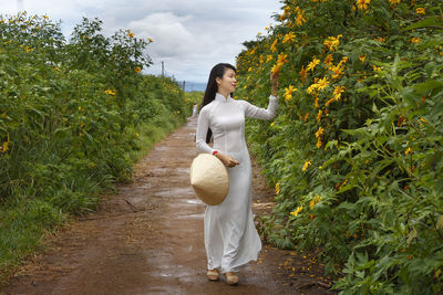 Full length of woman standing by plants against trees