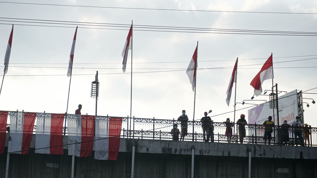 LOW ANGLE VIEW OF PEOPLE AGAINST CLOUDY SKY