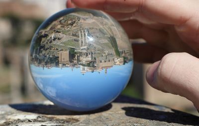 Close-up of hand holding crystal ball with reflection