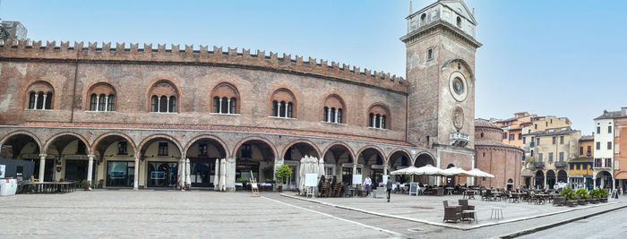  extra wide view of  square of erbe in mantua with historical buildings and a beautiful clock tower