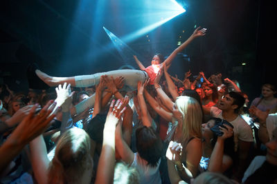 Group of people lifting singer at music concert