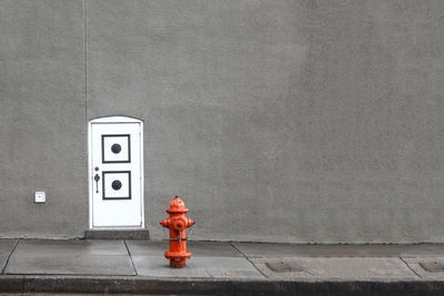 Fire hydrant on sidewalk against gray wall