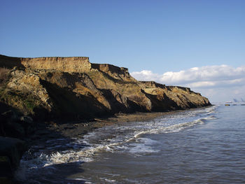 Rock formations on beach against sky