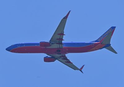 Low angle view of airplane flying against clear blue sky