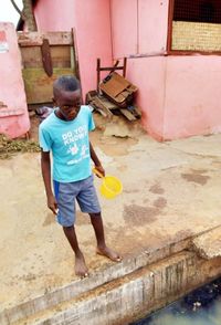 Full length of boy standing against brick wall