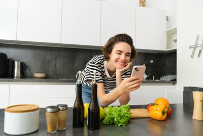 Portrait of young woman using mobile phone while sitting at home