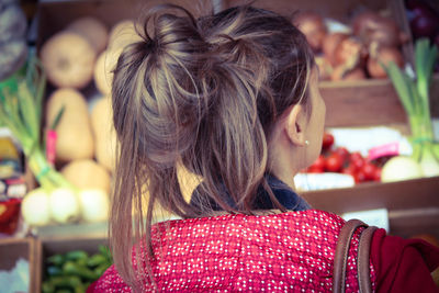 Rear view of woman buying fruits and vegetables at market