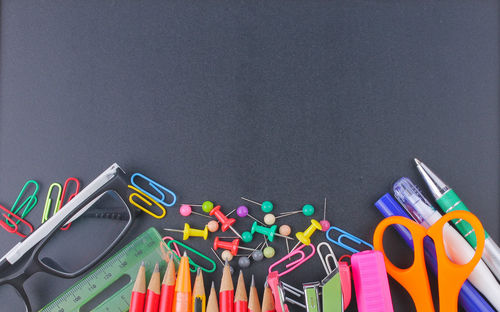 Directly above shot of school supplies on black table