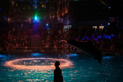 People standing by swimming pool at night