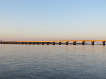 Pier over sea against clear sky during sunset