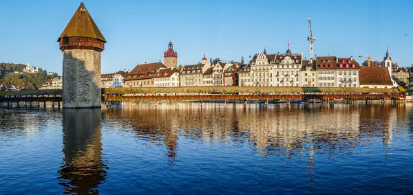 Luzern is reflected on the river on a sunny day with the chapel bridge