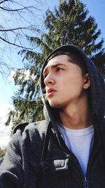 Portrait of woman standing by tree trunk