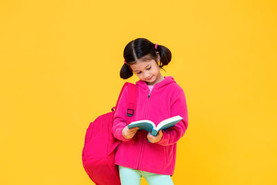 Portrait of a smiling girl holding yellow background