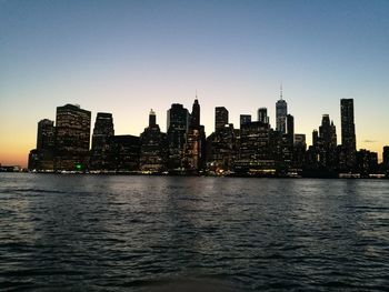 Sea by buildings against clear sky