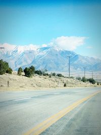 Country road leading towards snowcapped mountains