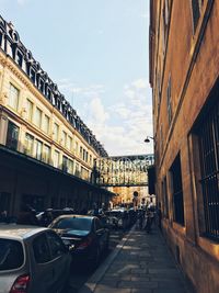 Cars on street in city against sky