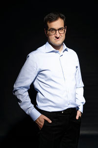 Portrait of young man standing against black background