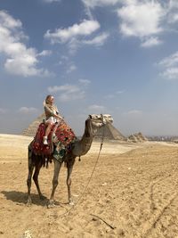 Man riding camel in desert against sky