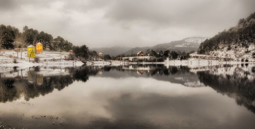 Scenic view of lake and mountains against cloudy sky