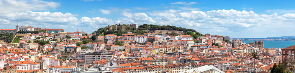 Aerial view of townscape by sea against sky