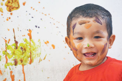 Portrait of cute boy with messy face against wall