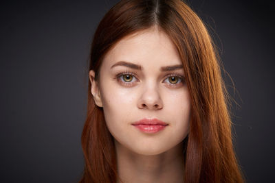 Close-up portrait of young woman against black background