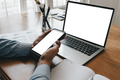 Midsection of man using mobile phone on table