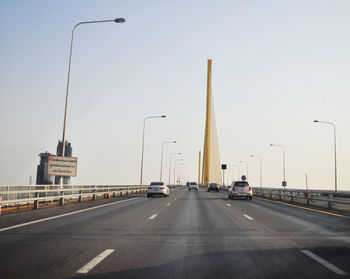 Vehicles on road against clear sky