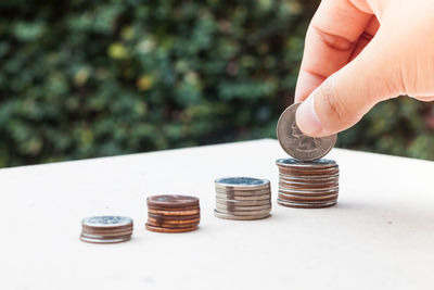 Cropped hand stacking coins on white table