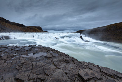 Scenic view of waterfall against sky