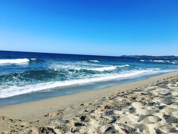 Scenic view of beach against clear blue sky