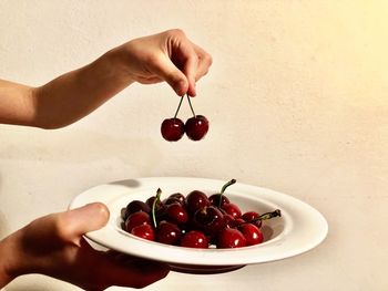 Close-up of hand holding cherries in bowl