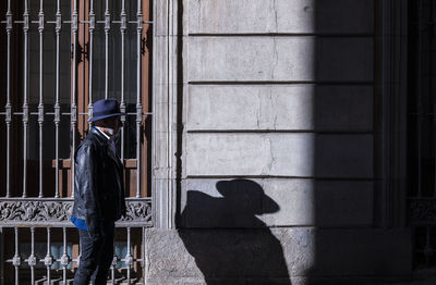 Adult man in hat and jacket walking on street with sunlight and shadow. madrid, spain